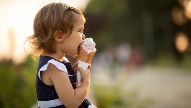 Beautiful baby girl eating ice cream on a sunny summer day