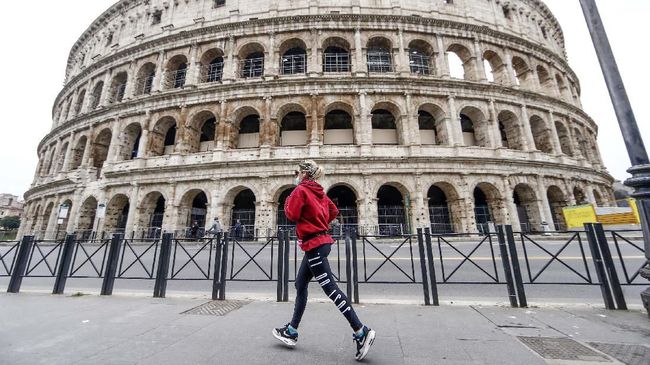 A woman runs by the Colosseum in Rome Friday, March 13, 2020. A sweeping lockdown is in place in Italy to try to slow down the spread of coronavirus epidemic. Among exception to the ordinance to remain home, there is the need for open air fitness. For most people, the new coronavirus causes only mild or moderate symptoms. For some, it can cause more severe illness, especially in older adults and people with existing health problems. (Cecilia Fabiano/LaPresse via AP)