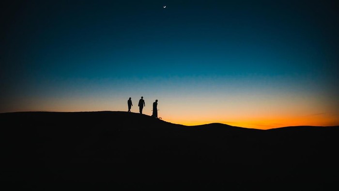 Arabs, Middle East, Culture - Three Arab men walking behind each other on the sand dunes