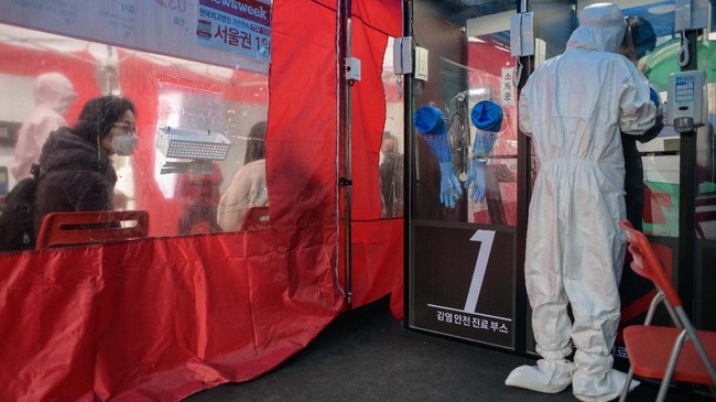 A woman watches from a waiting area as a nurse administers a COVID-19 novel coronavirus test at a testing booth outside Yangji hospital in Seoul on March 17, 2020. - A South Korean hospital has introduced 