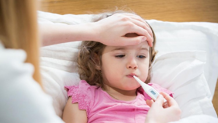 Close-up thermometer. Mother measuring temperature of her ill kid. Sick child with high fever laying in bed and mother holding thermometer. Hand on forehead.
