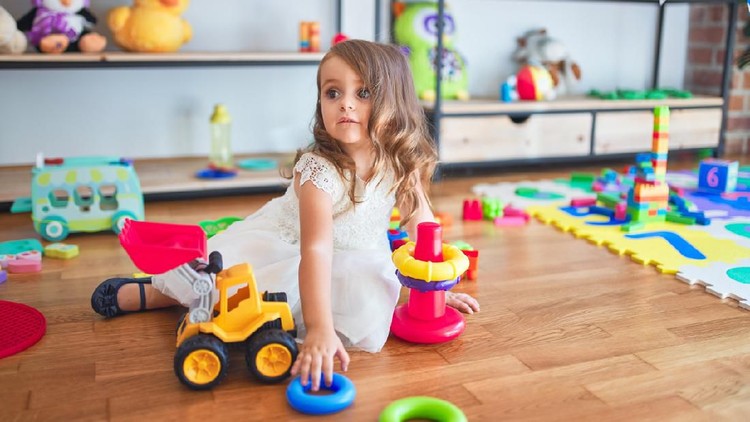 1204796097 Adorable blonde toddler building pyramid using hoops around lots of toys at kindergarten