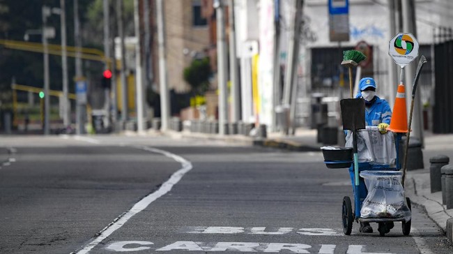 A cleaning worker wears a face mask as a preventive measure against the spread of the new coronavirus, COVID-19, in a street of Bogota on March 21, 2020. - Colombian President Ivan Duque announced mandatory preventive isolation from March 24 to April 13 as a measure against the spread of the novel coronavirus. (Photo by Juan BARRETO / AFP)