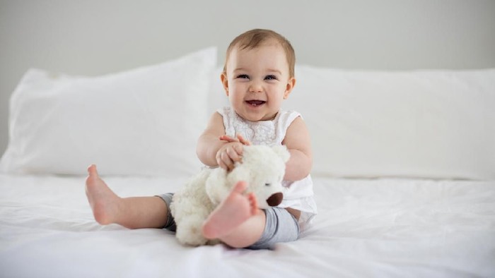 Sweet newborn baby sleeps in a basket. Beautiful newborn boy with bear toy.