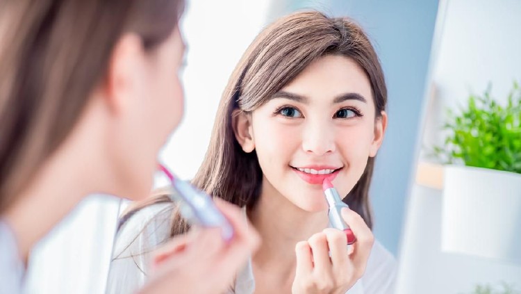 beauty woman applying lipstick and looking at mirror