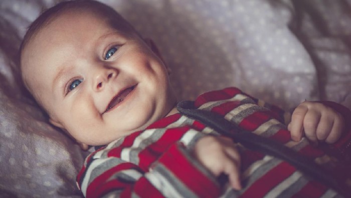 Adorable little baby boy, playing with toy, looking curiously at camera