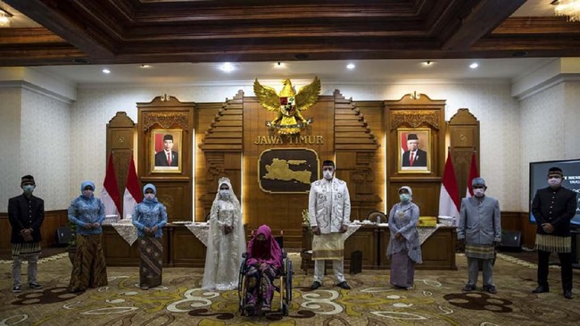 Family members and a limited number of guests wearing face masks, amid concerns of the COVID-19 coronavirus, stand apart during the wedding ceremony of Indonesian bride Irra Chorina Octora and her Turkish partner Yavuz Ozdemir in Surabaya on March 25, 2020. (Photo by Juni Kriswanto / AFP)