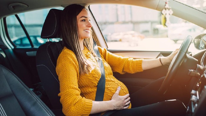 Pregnant woman driving with safety belt on in the car.