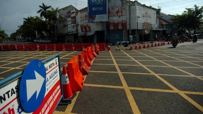 Kendaraan melintas samping pembatas  jalan di kawasan  perempatan Alun-alun Kota Tegal, Jawa Tengah, Jumat (27/3/2020).  Sejak diberlakukan  penutupan jalan masuk ke Alun-alun Kota Tegal  dan pengalihan jalur di sejumlah jalan protokol untuk antisipasi penyebaran COVID-19 lima hari lalu, jalanan di pusat kota llengang dan  penjualan  sejumlah toko dan rumah makan diperkirakan menurun hingga 80 persen. ANTARA FOTO/Oky Lukmansyah/nz