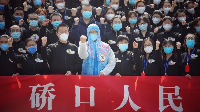 Members of a medical assistance team from Jiangsu province chant slogans at a ceremony marking their departure after helping with the COVID-19 coronavirus recovery effort, in Wuhan, in China's central Hubei province on March 19, 2020. - Medical teams from across China began leaving Wuhan this week after the number of new coronavirus infections dropped. China on March 19 reported no new domestic cases of the coronavirus for the first time since it started recording them in January, but recorded a spike in infections from abroad. (Photo by STR / AFP) / China OUT