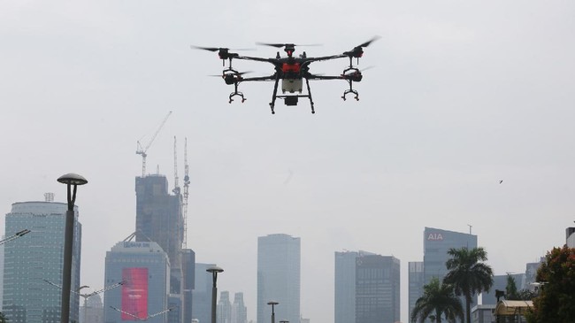 Sebuah drone menyemprotkan disinfektan dari ketinggian di kawasan Jalan Jenderal Sudirman,, Jakarta, Jumat (27/3/2020). Penyemprotan disinfektan tersebut dilakukan guna menekan penyebaran virus Corona (COVID-19). ANTARA FOTO/Reno Esnir/nz.