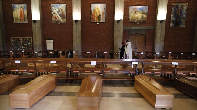 Don Marcello Crotti, right, walks with Don Mario Carminati as they bless coffins inside the San Giuseppe church in Seriate, Italy, Saturday, March 28, 2020. The new coronavirus causes mild or moderate symptoms for most people, but for some, especially older adults and people with existing health problems, it can cause more severe illness or death. (AP Photo/Antonio Calanni)