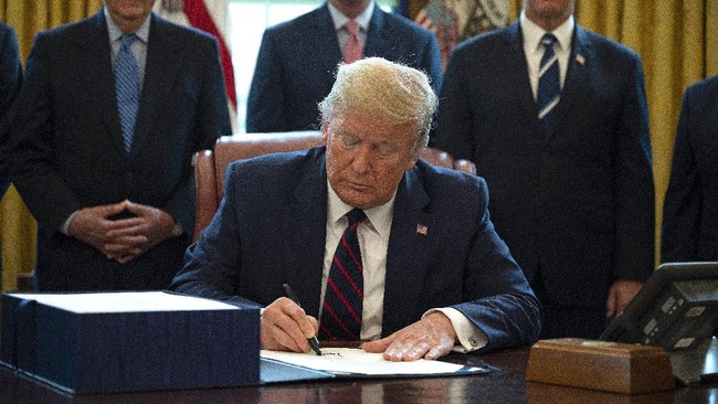 US President Donald Trump, flanked by US Senate Majority Leader Mitch McConnell (L), House Minority Leader Kevin McCarthy (C) and Vice President Mike Pence (R), signs the CARES act, a $2 trillion rescue package to provide economic relief amid the coronavirus outbreak, at the Oval Office of the White House on March 27, 2020. - After clearing the Senate earlier this week, and as the United States became the new global epicenter of the pandemic with 92,000 confirmed cases of infection, Republicans and Democrats united to greenlight the nation's largest-ever economic relief plan. (Photo by JIM WATSON / AFP)