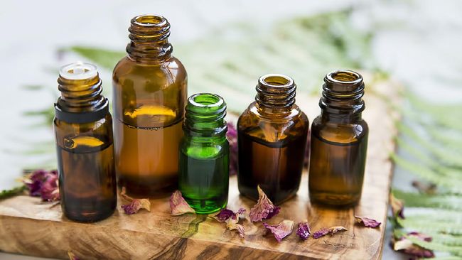Aromatherapy oil bottles with flowers and green leaves, botanical natural alternative beauty, herbal wellness and spa setting