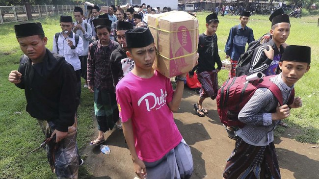 Sejumlah santri berjalan menuju bus untuk dipulangkan ke daerah asal di Pondok Pesantren (Ponpes) Lirboyo, Kota Kediri, Jawa Timur, Selasa (31/3/2020). Ponpes terbesar se-Jawa Timur tersebut memulangkan sedikitnya 22 ribu santri untuk menangkal penyebaran COVID-19. ANTARA FOTO/Prasetia Fauzani/wsj.