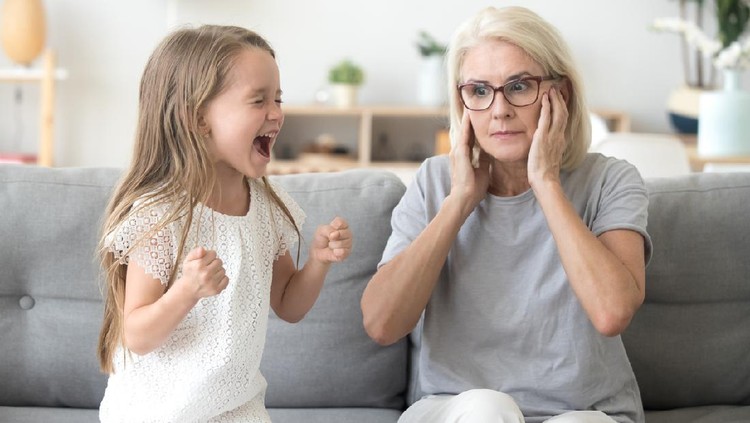 Stressed exhausted mother looking at camera feeling desperate about screaming stubborn kid daughter tantrum, upset annoyed mom tired of naughty difficult child girl misbehave yelling for attention