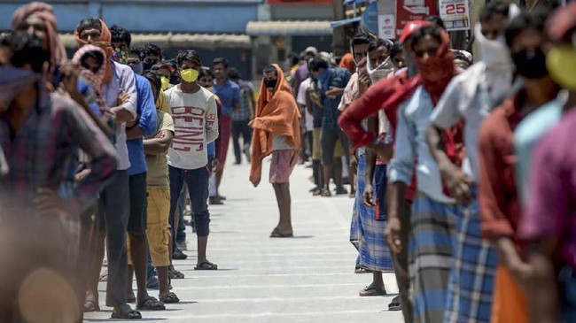 Migrant workers wait on marked areas on the ground to maintain social distancing as they queue to receive food packets at an industrial area during a government-imposed nationwide lockdown as a preventive measure against the COVID-19 coronavirus, in Chennai on April 1, 2020. (Photo by Arun SANKAR / AFP)