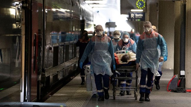 Medical staff carry a patient infected with the COVID-19 into a TGV high speed train at the Gare d'Austerlitz train station on April 1, 2020 in Paris, prior to his evacuation, along with 35 other patients in two separate medical TGV towards hospitals of Brittany, western France, where the outbreak of the Covid-19 pandemic caused by the novel coronavirus where has been limited so far. (Photo by Thomas SAMSON / POOL / AFP)