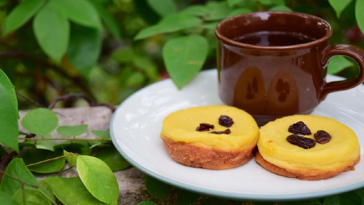 1022855706 Kue Lumpur, Indonesian cuisine, made from potato, egg, coconut milk, butter, flour and sugar garnish with raisin. Served with cup of tea. Snack for breaking the fast or buka puasa