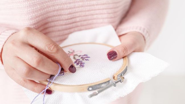 cross-stitched pillow in female hands