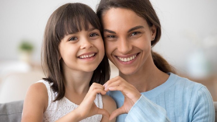Loving single mother hugging cute little daughter kissing kid sitting on sofa, happy woman mum caressing embracing preschool girl, moms care and support, sincere warm relationships for child concept