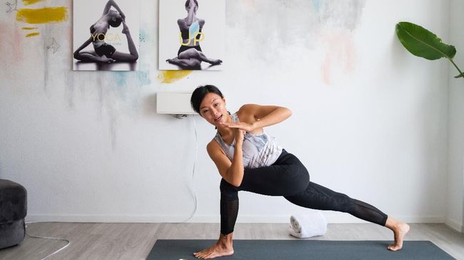In this picture taken on March 30, 2020, YogaUP founder Chaukei Ngai demonstrates the Revolved High Lunge Twist (Parivrtta Ashtachandrasana) as she leads a live streamed yoga class via the Zoom online video conferencing platform, at her studio in Discovery Bay, on the outlying Lantau Island in Hong Kong. - More than 3.4 billion people have been called on or forced by authorities to stay at home, around 44 percent of the world population, according to a count based on an AFP database. Many are wondering how they can stay healthy during the weeks -- and possibly months -- of self-isolation that lie ahead. Hong Kongers, who live in some of the world's smallest apartments, say it can be done. (Photo by Anthony WALLACE / AFP) / TO GO WITH HongKong-health-virus-fitness,FOCUS by Jerome TAYLOR