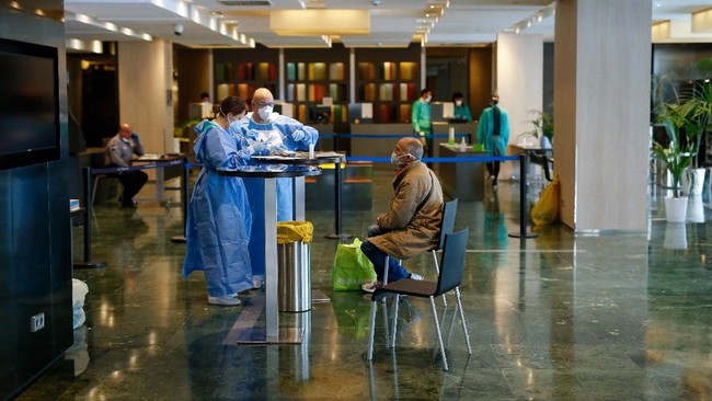 Healthcare workers attends to a COVID-19 patient upon his arrival at the Hotel Melia Barcelona Sarria on April 2, 2020 in Barcelona, as the hotel was transformed into a medical structure to treat the least serious cases amid the outbreak caused by the novel coronavirus. - The coronavirus death toll in Spain surged past 10,000 after a record 950 deaths in 24 hours, with the number of confirmed cases passing the 110,000 mark, the government said. (Photo by PAU BARRENA / AFP)