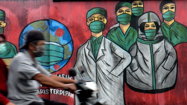 Pengendara motor melintas di depan mural tentang pandemi virus corona atau COVID-19 di Jalan Raya Jakarta-Bogor, Depok, Jawa Barat, Jumar (3/4/2020). Mural tersebut ditujukan sebagai bentuk dukungan kepada tenaga medis yang menjadi garda terdepan dalam menghadapi COVID-19 di Indonesia. ANTARA FOTO/Yulius Satria Wijaya/pras.