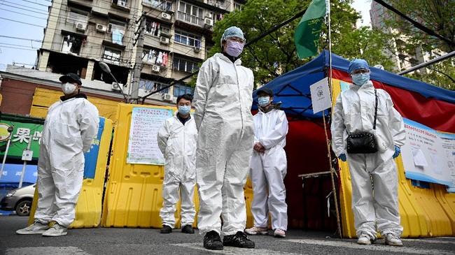 Community volunteers wearing hazmat suits observe three minutes of silence to mourn those who died in the fight against the pandemic along a street in Wuhan, in Chinaís central Hubei province on April 4, 2020. - China came to a standstill to mourn patients and medical staff killed by the coronavirus, with the world's most populous country observing a nationwide three-minute silence. (Photo by Noel Celis / AFP)