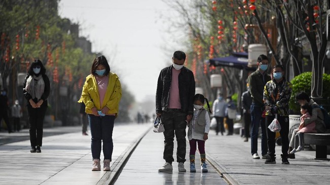 People wearing face masks mourn patients and medical staff killed by coronavirus during a nationwide three minutes silence along a business street in Beijing on April 4, 2020. - China came to a standstill to mourn patients and medical staff killed by the coronavirus, with the world's most populous country observing a nationwide three-minute silence. (Photo by WANG ZHAO / AFP)