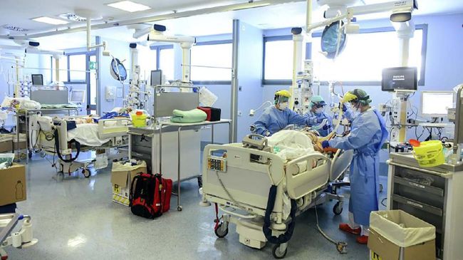 Angka Kematian Virus Corona Capai 153 Ribu Orang Member of the medical staff take care of a patient infected by the novel coronavirus, at the COVID-19 division at the ASST Papa Giovanni XXIII hospital in Bergamo, on April 3, 2020. - Italy's three-week lockdown to stop the spread of COVID-19 has been extended through at least mid-April and its economy is expected to suffer its biggest peacetime shock since World War II. (Photo by Piero CRUCIATTI / AFP)