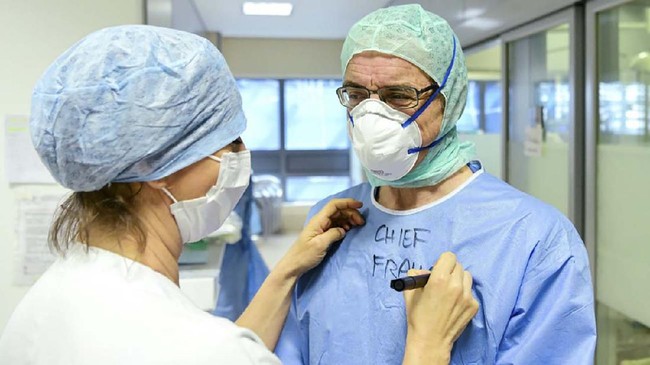 A member of the medical writes the name of a doctor on his Personal Protective Equipment (PPE) at the COVID-19 division at the ASST Papa Giovanni XXIII hospital in Bergamo, on April 3, 2020. - Italy's three-week lockdown to stop the spread of COVID-19 has been extended through at least mid-April and its economy is expected to suffer its biggest peacetime shock since World War II. (Photo by Piero CRUCIATTI / AFP)