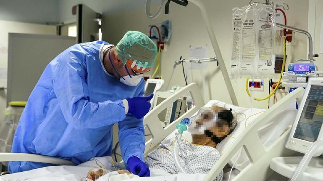 A member of the medical staff comforts a patient infected by the novel coronavirus at the COVID-19 division at the ASST Papa Giovanni XXIII hospital in Bergamo, on April 3, 2020. - Italy's three-week lockdown to stop the spread of COVID-19 has been extended through at least mid-April and its economy is expected to suffer its biggest peacetime shock since World War II. (Photo by Piero CRUCIATTI / AFP)