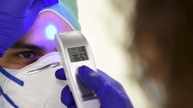 A member of the medical staff wearing his Personal Protective Equipment (PPE) has his temperature taken while working at the COVID-19 division at the ASST Papa Giovanni XXIII hospital in Bergamo, on April 3, 2020. - Italy's three-week lockdown to stop the spread of COVID-19 has been extended through at least mid-April and its economy is expected to suffer its biggest peacetime shock since World War II. (Photo by Piero CRUCIATTI / AFP)