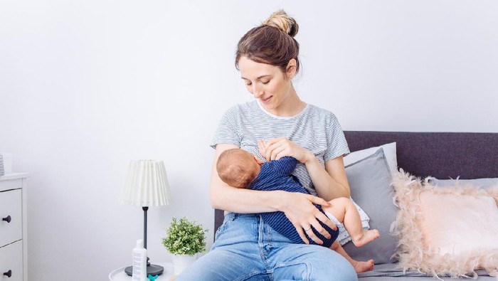 Mother breastfeeding baby son in bedroom, they enjoy in this moment together