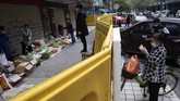 Salah satu pedagang yang bertahan dari balik tembok mengatakan usahanya tetap berjalan dengan transaksi terjadi dari sisi berbeda dengan pembeli. (AP Photo/Ng Han Guan)