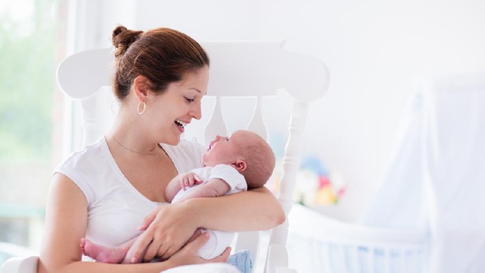 Mother breastfeeding baby son in bedroom, they enjoy in this moment together