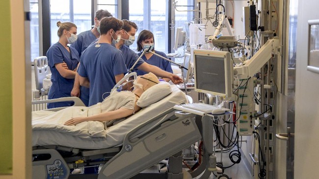 In this Tuesday, March 25, 2020, photo, hospital doctors get instructions on a ventilator at the University Hospital Eppendorf in Hamburg Germany. Germany has seen a steady rise in the number of new coronavirus infections, but so far deaths have been low compared to many of its European neighbors.  (Axel Heimken/Pool Photo via AP)