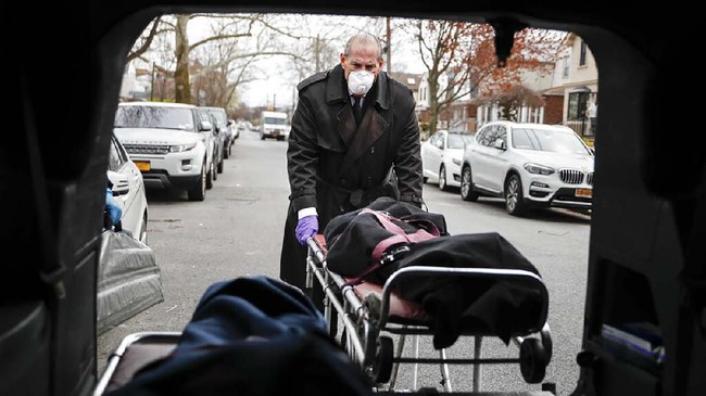Funeral director Tom Cheeseman loads a body into his van after making a house call, Friday, April 3, 2020, in the Brooklyn borough of New York. The Associated Press spent a day on the road with Cheeseman, who is overwhelmed by demand due to the coronavirus outbreak. Cheeseman is picking up as many as 10 bodies per day. Most bodies come from homes and hospitals. “We took a sworn oath to protect the dead, this is what we do,” he said. (AP Photo/John Minchillo)