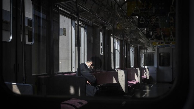 A man wearing a face mask amid concerns over the spread of the COVID-19 coronavirus travels on a train in Tokyo on April 6, 2020. (Photo by Philip FONG / AFP)