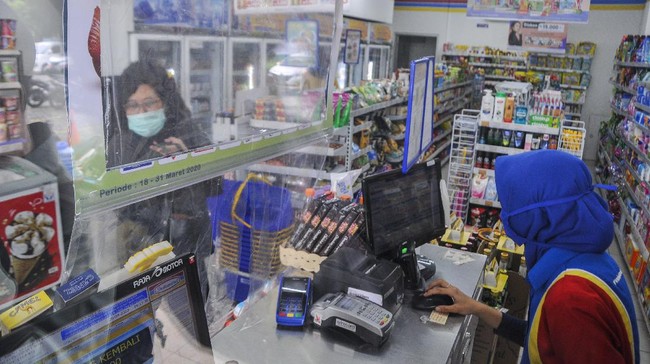 Pembeli melakukan pembayaran dari balik plastik pembatas di salah satu minimarket daerah Bekasi, Jawa Barat, Rabu (8/4/2020). Penggunaan plastik pembatas tersebut bertujuan untuk mengantisipasi penyebaran virus COVID-19. ANTARA FOTO/ Fakhri Hermansyah/foc.