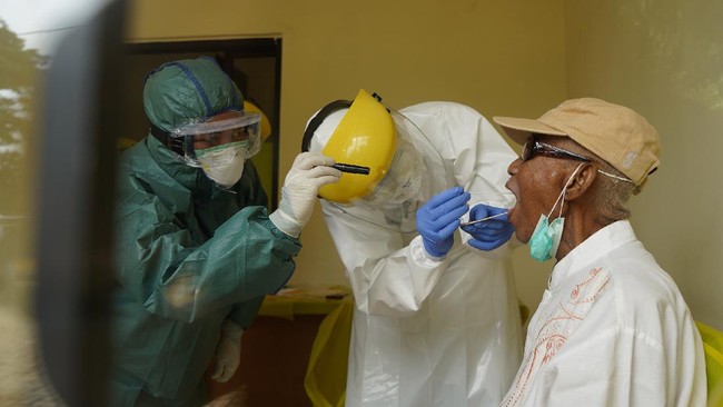 An Indonesian medical team takes a swab from a man to test for the COVID-19 coronavirus in Depok on April 6, 2020. (Photo by STR / AFP)