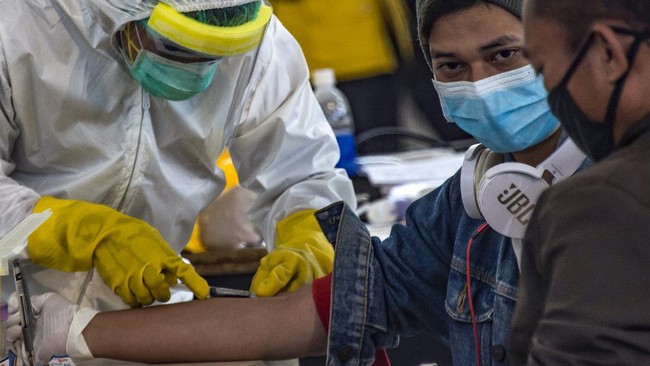 Indonesian officials conduct health screening on 156 migrant workers who arrived from Malaysia at Surabaya airport in Indonesia's East Java on April 7, 2020, amid concerns of the spread of the COVID-19 coronavirus. (Photo by Juni Kriswanto / AFP)