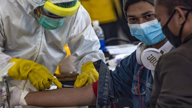 Pandemi Corona di Indonesia Diprediksi Berakhir 3 Juni Indonesian officials conduct health screening on 156 migrant workers who arrived from Malaysia at Surabaya airport in Indonesia's East Java on April 7, 2020, amid concerns of the spread of the COVID-19 coronavirus. (Photo by Juni Kriswanto / AFP)