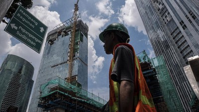 Pekerja melintas dengan latar belakang pembangunan gedung bertingkat di kawasan Kuningan, Jakarta, Jumat (3/4/2020). Bank Indonesia (BI) mengoreksi proyeksi pertumbuhan ekonomi Indonesia paling rendah 2,3 persen pada tahun ini yang akan ditopang oleh berbagai stimulus, baik fiskal maupun moneter yang diberikan oleh pemerintah dan bank sentral. ANTARA FOTO/Dhemas Reviyanto/pras.