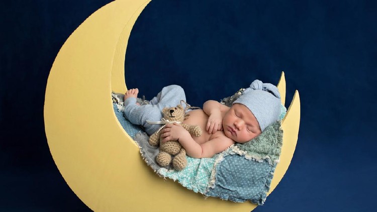 Cute newborn baby girl lying in the bed. 2 month old child in owl hat sleeping on blue blanket with stars