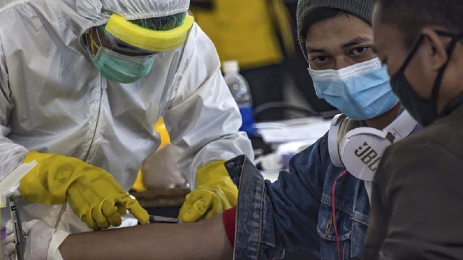 Indonesian officials conduct health screening on 156 migrant workers who arrived from Malaysia at Surabaya airport in Indonesia's East Java on April 7, 2020, amid concerns of the spread of the COVID-19 coronavirus. (Photo by Juni Kriswanto / AFP)