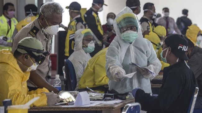 Indonesian officials conduct health screening on 156 migrant workers who arrived from Malaysia at Surabaya airport in Indonesia's East Java on April 7, 2020, amid concerns of the spread of the COVID-19 coronavirus. (Photo by JUNI KRISWANTO / AFP)