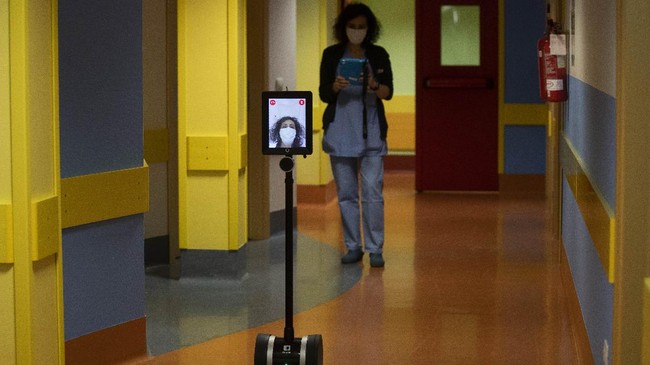 Nurse Helga drives 'Ivo' a tablet supported by a periscopic pole mounted on wheels at 'Ospedale di Circolo' in Varese, Italy, Wednesday, April 8, 2020. Ivo is remotely controlled by the healthcare professional via smartphone. It can enter the rooms and, with a video call system, put the staff in communication with the patients. The new coronavirus causes mild or moderate symptoms for most people, but for some, especially older adults and people with existing health problems, it can cause more severe illness or death. (AP Photo/Luca Bruno)