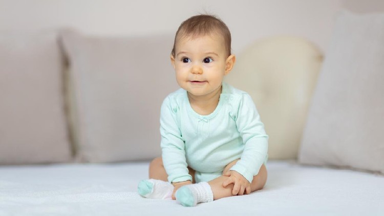 1136048166 baby girl on the bed among pillows
